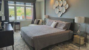 A bedroom with a large bed, a desk, a chair, and a view of greenery outside. - Prime View of Fountain and Channel ~ Great location!   (Grand Haven)