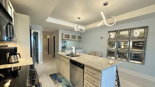 A modern kitchen with a central island, stainless steel appliances, and a backsplash of mirrors. - Prime View of Fountain and Channel ~ Great location!   (Grand Haven)