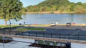 A parking lot with a view of a lake and a forested hill in the background. - Prime View of Fountain and Channel ~ Great location!   (Grand Haven)