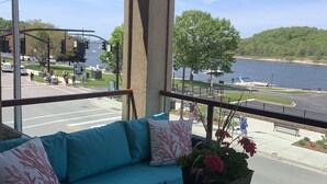 A balcony with a blue sofa, a glass table, and a potted plant. - Prime View of Fountain and Channel ~ Great location!   (Grand Haven)