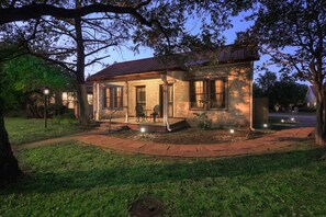 A small stone house with a porch, a pathway, and outdoor lighting. - 1880's Charmer w/ 5 Suites, 1.5blks to Main, firepit, large patio (Fredericksburg)