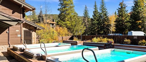 A pool area with hot tubs and a wooden deck.