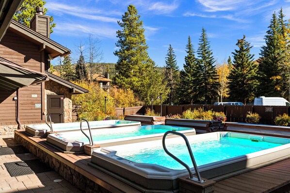 A pool area with hot tubs and a wooden deck.