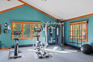 A gym with exercise equipment, large windows, and a view of the outdoors.