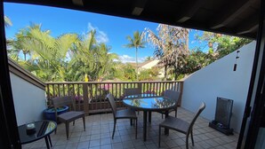 Eine überdachte Terrasse mit rundem Tisch und Stühlen, einem kleinen Pool und einem Grill.