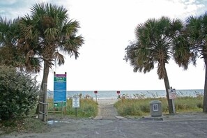 A beach entrance with palm trees, a signboard, and a view of the ocean. - Grand Ocean Getaway III, Private Pool ! (North Myrtle Beach)