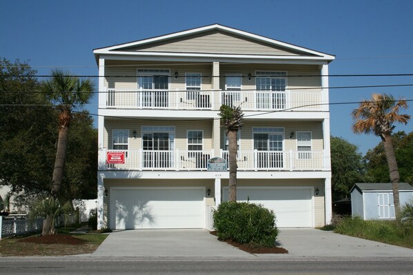 A two-story residential building with a white exterior, a balcony on the upper floor, and a garage at the front. - Grand Ocean Getaway III, Private Pool ! (North Myrtle Beach)