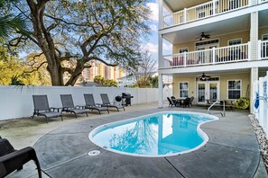 A pool area with lounge chairs, a barbecue grill, and a two-story building with balconies. - Grand Ocean Getaway III, Private Pool ! (North Myrtle Beach)