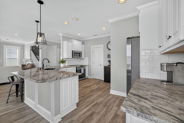 A modern kitchen with white cabinetry, a granite countertop, and a central island.