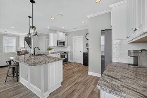 Una cocina moderna con armarios blancos, encimera de granito y una isla central.