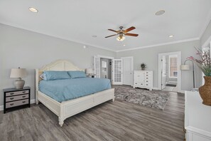 A bedroom with a bed, nightstands, a dresser, a ceiling fan, and a rug.