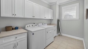 A laundry room with white cabinets, a washing machine, and a dryer.