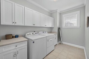 Une buanderie avec des armoires blanches, un lave-linge et un sèche-linge.