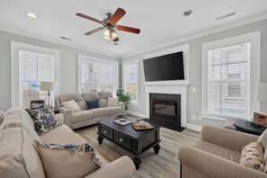 A living room with a sofa, coffee table, fireplace, and a ceiling fan.