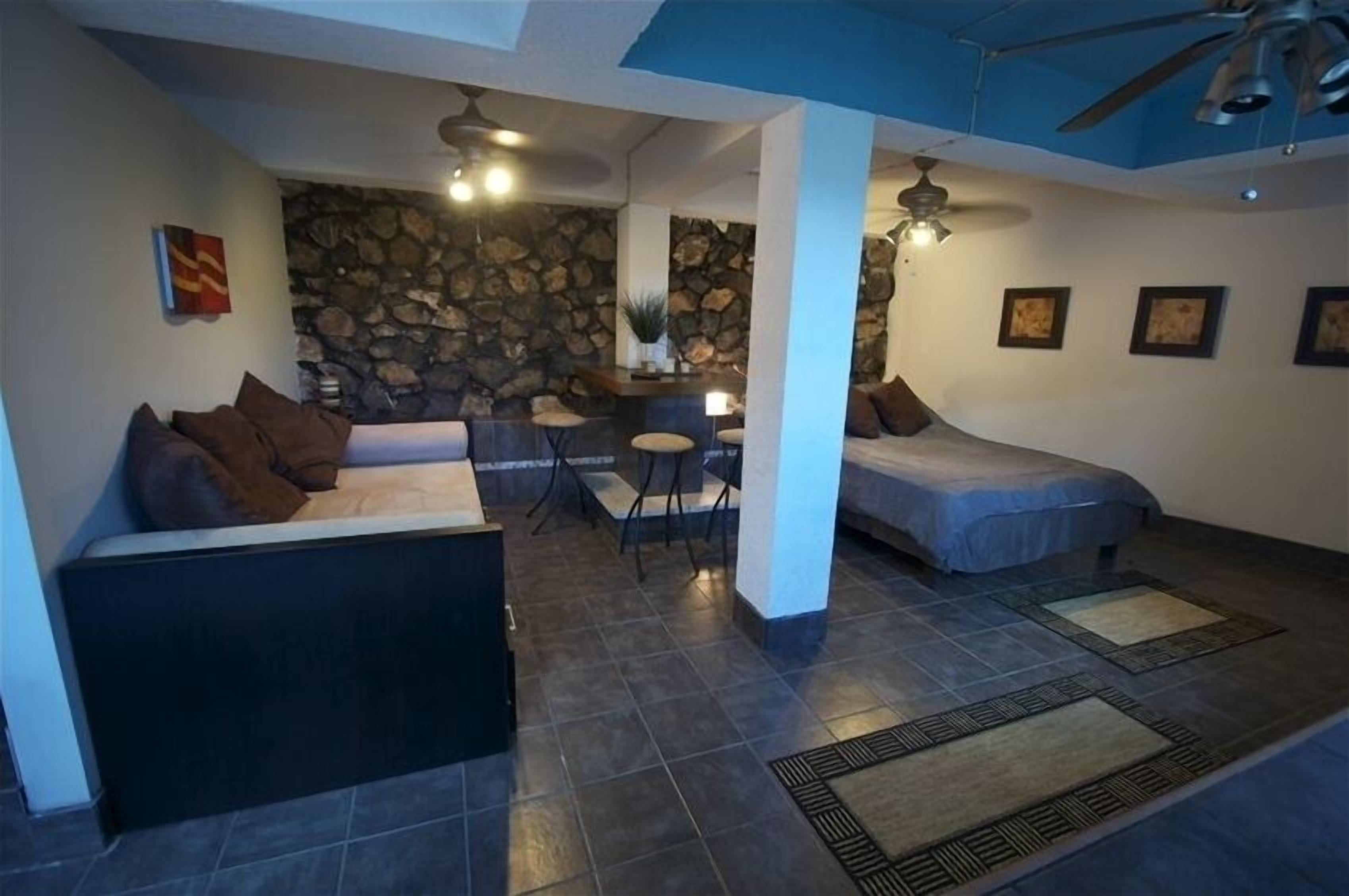 A cozy living area with a stone wall, a sofa, a bed, and a dining table.
