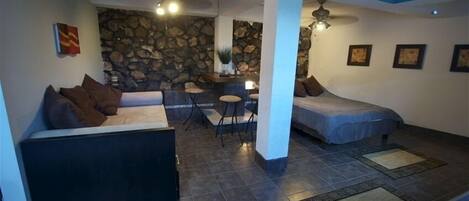 A cozy living area with a stone wall, a sofa, a bed, and a dining table.