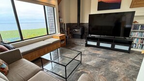 A living room with a large window, a fireplace, a television, and a bookshelf.