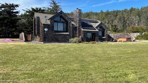 A modern two-story house with a stone facade, large windows, and a well-maintained lawn.