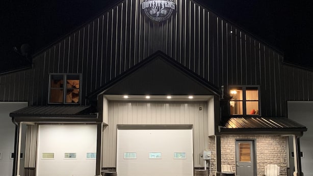 A large, modern building with a prominent sign reading "Outdoors." It features a large garage door, multiple windows, and a well-lit entrance. - Lofty Lodge on the Bourbon Trail  (Springfield)