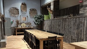 A spacious dining area with a long wooden table and chairs, surrounded by a rustic wooden wall and a corrugated metal wall with decorative items. - Lofty Lodge on the Bourbon Trail  (Springfield)