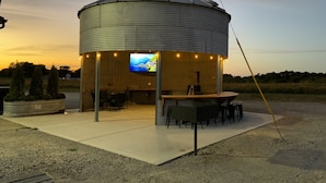 A cylindrical outdoor structure with a flat roof, a mounted television screen, and a seating area with tables and chairs. - Lofty Lodge on the Bourbon Trail  (Springfield)