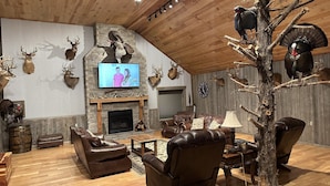 A cozy living room with a fireplace, leather furniture, and various animal mounts on the walls. - Lofty Lodge on the Bourbon Trail  (Springfield)