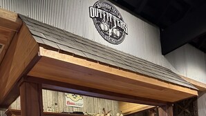 A rustic bar area with wooden furniture, a television screen, and a sign reading "Outletter." - Lofty Lodge on the Bourbon Trail  (Springfield)