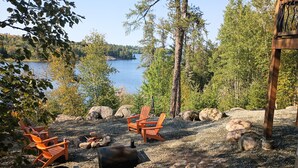 En sittplats vid sjön med utemöbler och en grill.
