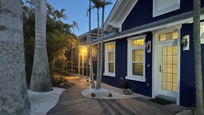 A modern house with a dark blue exterior, white trim, and a wooden pathway leading to the entrance. - 🏝 LOCAL LANDMARK.         The BLUE HOUSE on PINE 🐬Casa Caliente🐬 (Anna Maria)