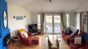 Een woonkamer met een open haard, rode banken, een houten salontafel en een televisie.