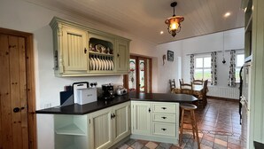 Een keuken met lichtgroene kastjes, een zwart aanrecht en een hangende lamp.