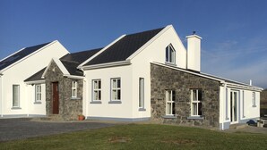 Een huis met twee verdiepingen, een stenen gevel en een witte buitenkant.