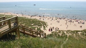 Une plage avec une promenade en bois qui mène au rivage, une plage de sable et l’océan.