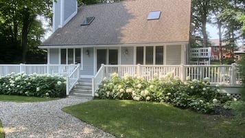 Stunning two-story home with a central chimney, covered porch, and beautifully manicured lawn.