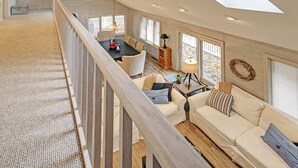Un loft spacieux avec un plafond haut, un coin repas comprenant une table et des chaises, un ensemble de canapés et une vue dégagée grâce à de grandes fenêtres.