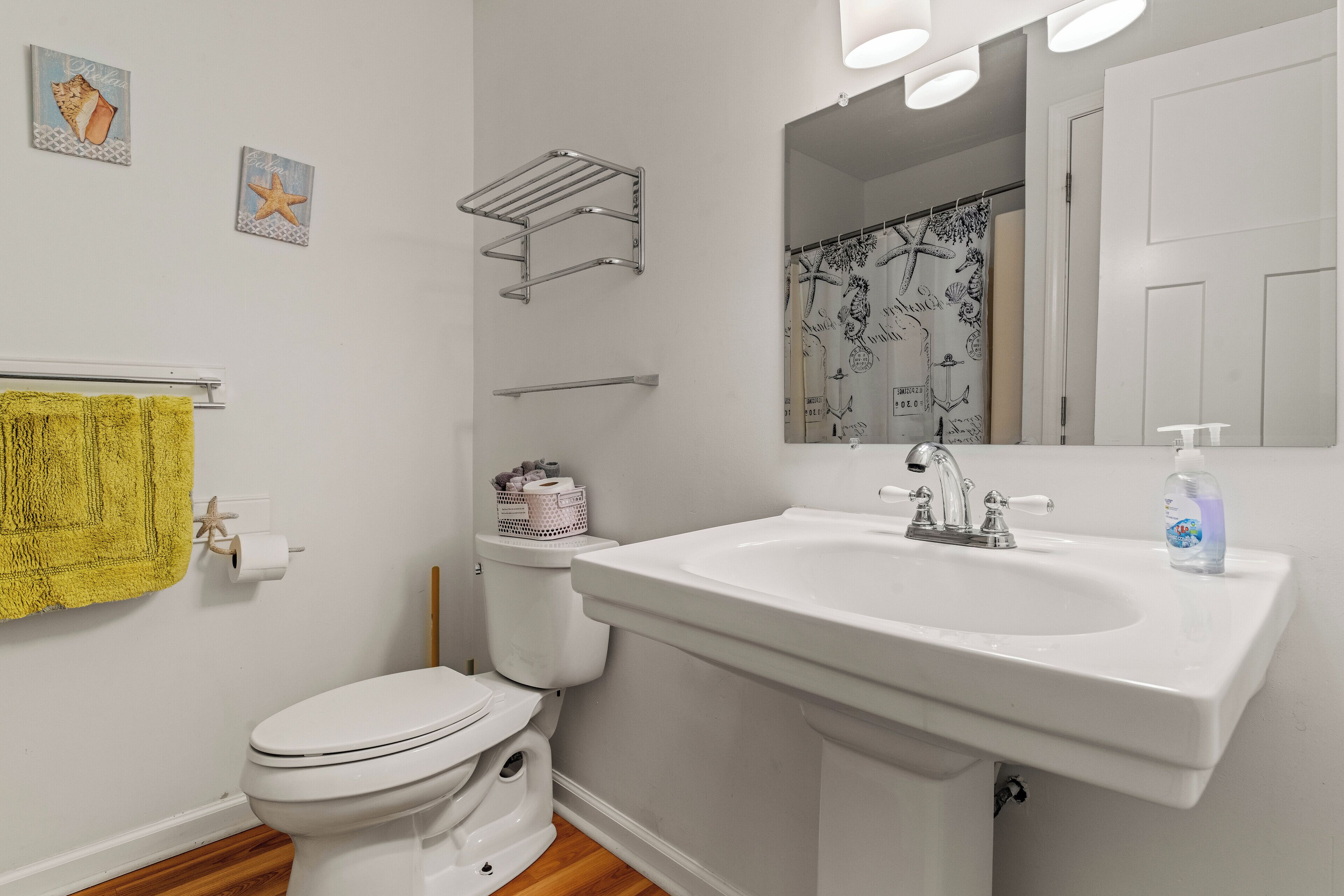 A bathroom with a white sink, toilet, and a shower curtain with a starfish design.