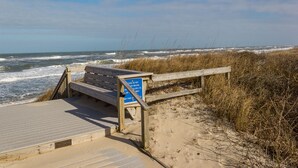 Eine Holzbank und ein Schild an einer Uferpromenade.