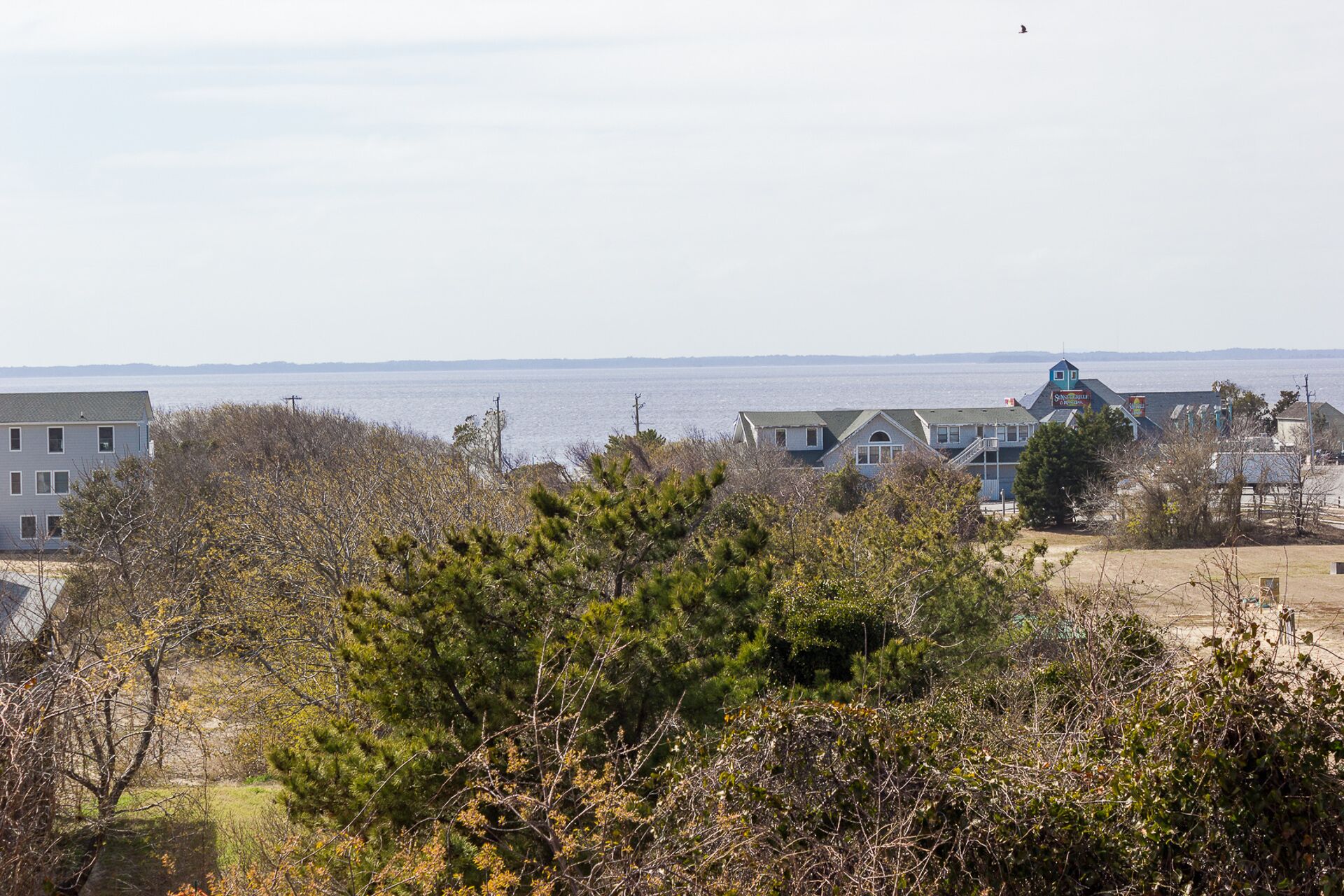 A coastal view with houses, a beach, and a clear sky.