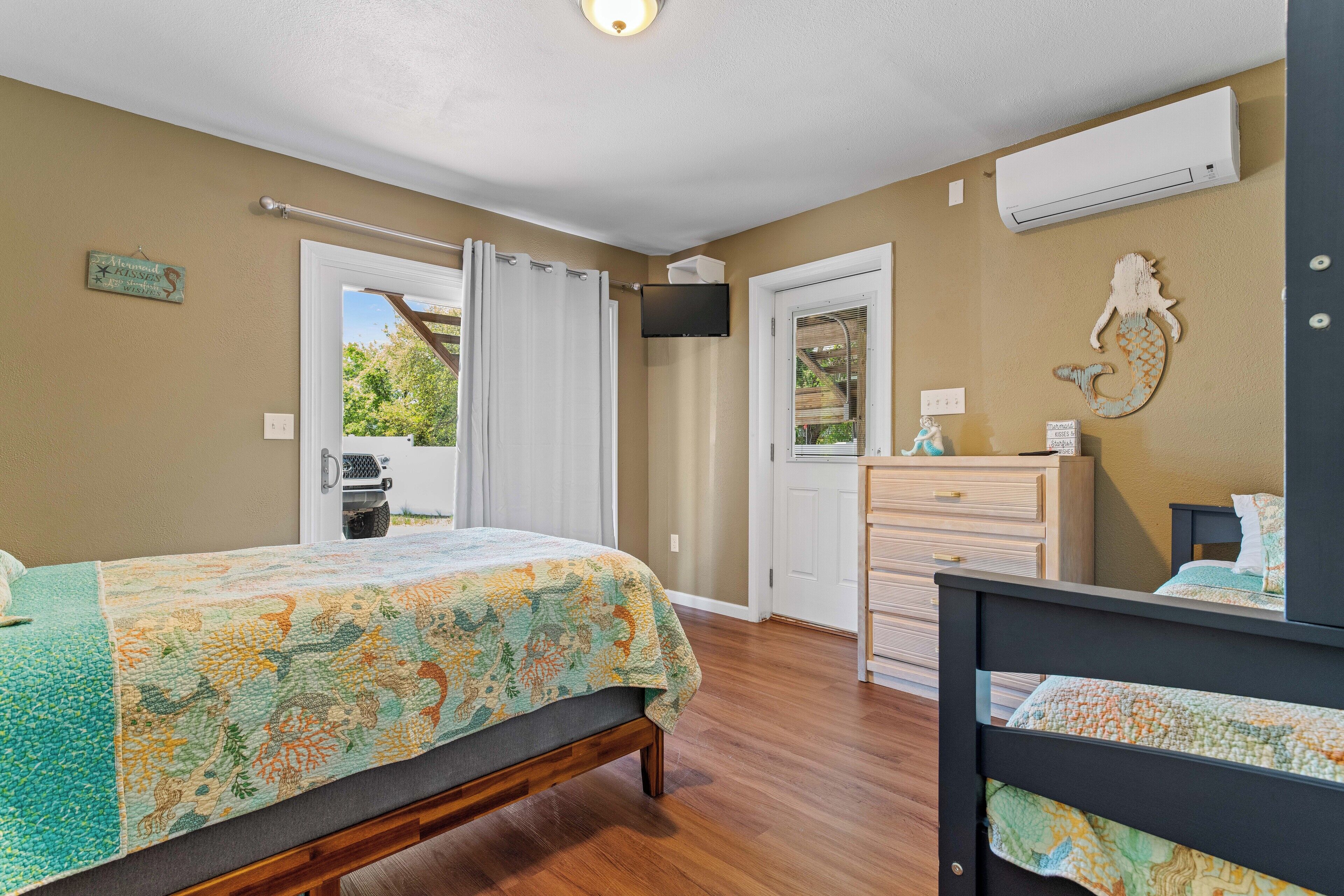 A bedroom with a bed, dresser, and an air conditioning unit.