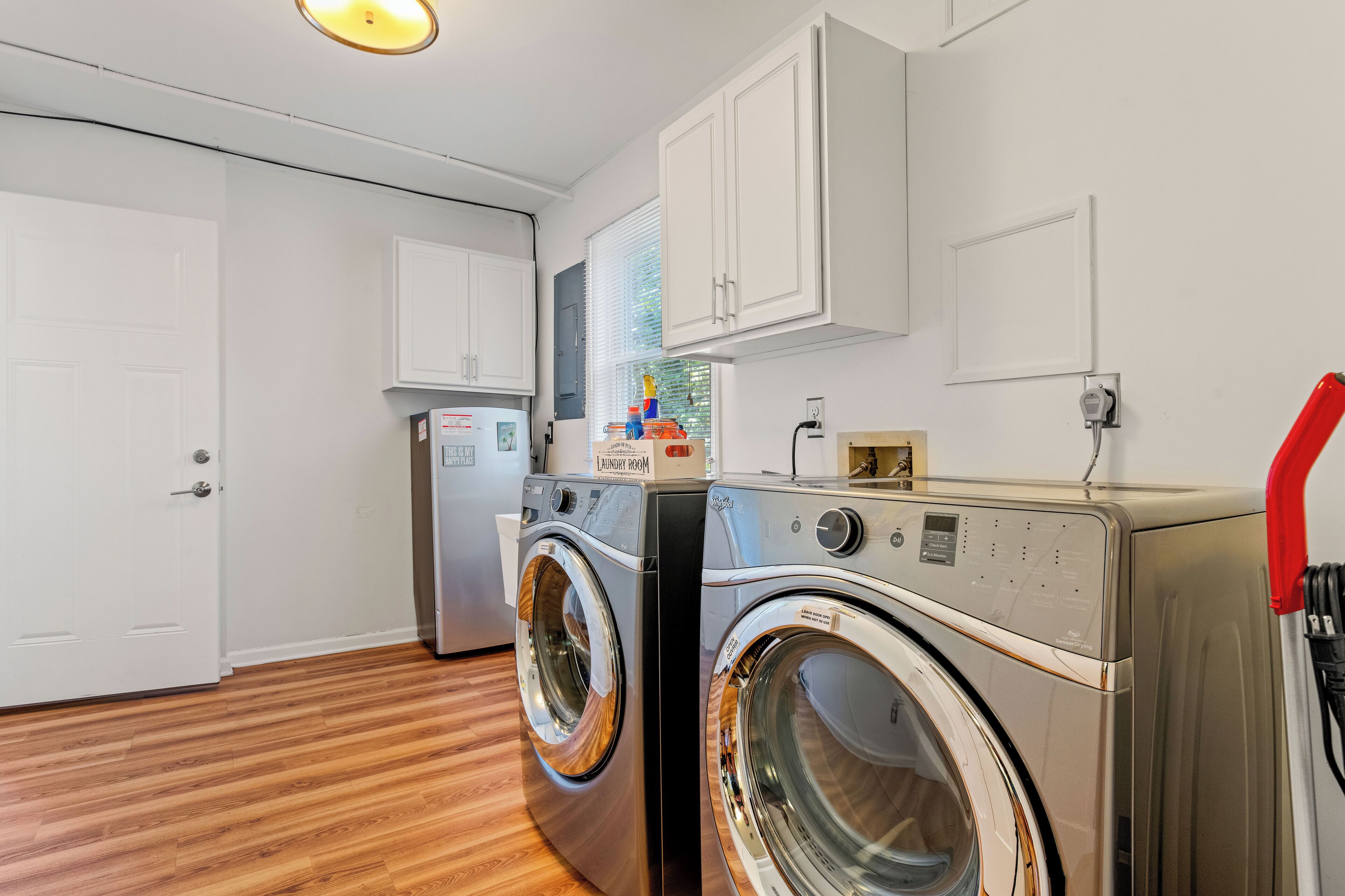 A laundry room with two front-loading washing machines, a dryer, and a small refrigerator.