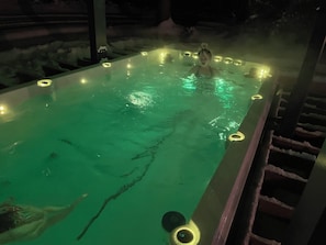 A hot tub with a person in it, surrounded by lights.