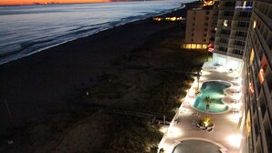 Un hôtel doté de plusieurs piscines, offrant une vue sur la plage et disposant d’un espace extérieur bien éclairé.