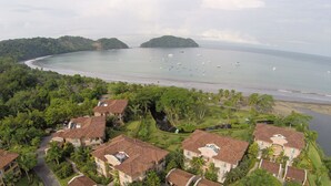 A coastal residential area with houses, a beach, and boats in the water. - Luxury Oceanfront Los Suenos Condo overlooking Herradura Bay (Los Suenos)
