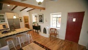 A spacious kitchen with a large island, white bar stools, and a wooden dining table.