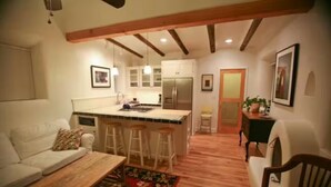 A cozy living room with a wooden coffee table, a sofa, and a kitchen area with a bar stool.