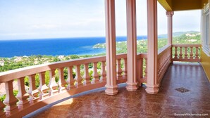 Un balcone con colonne e ringhiera che si affaccia su una vista costiera.