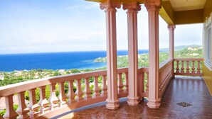 Un balcon doté de colonnes et d’une balustrade, offrant une vue sur la côte.