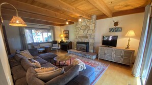 A cozy living room with a large sectional sofa, a stone fireplace, a television, and a stone wall. - Private neighborhood beach, gated community. 3 miles from casinos -8ppl (Zephyr Cove)