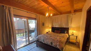 A bedroom with a large bed, a wooden ceiling, a sliding glass door to a deck, and two bedside lamps. - Private neighborhood beach, gated community. 3 miles from casinos -8ppl (Zephyr Cove)