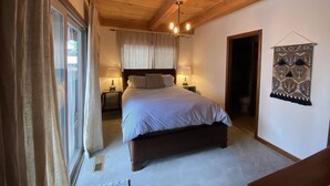 A bedroom with a wooden ceiling, a bed with a headboard, two bedside tables with lamps, a window with curtains, and a wall hanging. - Private neighborhood beach, gated community. 3 miles from casinos -8ppl (Zephyr Cove)